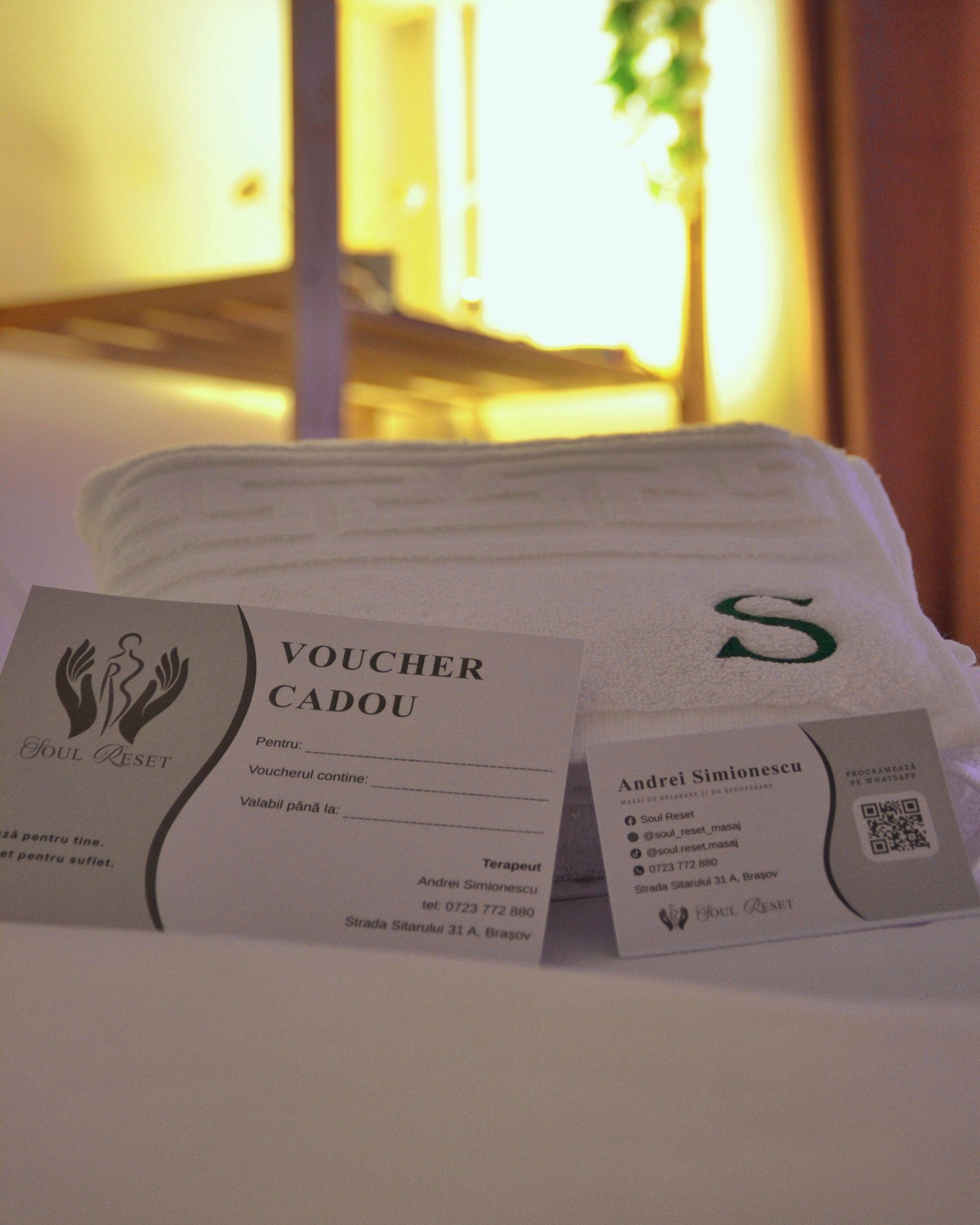 Voucher cadou și carte de vizită Soul Reset, sprijinite de un prosop cu monograma S.